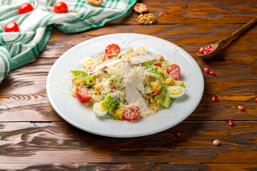 Salad caesar with chicken on white plate on wooden table