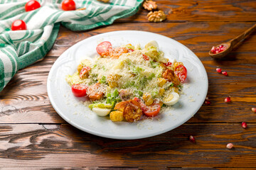 salad caesar with shrimps on white plate on wooden table