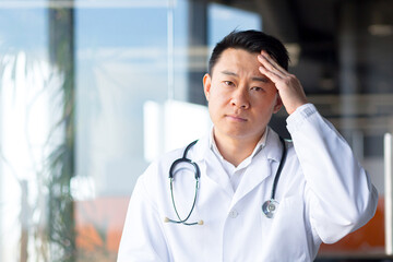 Close-up photo of an Asian doctor tired of work, has a severe headache in the clinic