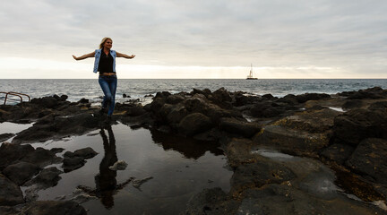 Women on volcanic rocks and blue ocean with waves, white foam and volcanic rocks. Canary Islands. The magnificent coast of the Atlantic Ocean © Angelov