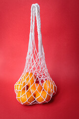 Eco-friendly mesh with tangerines on a red festive background.