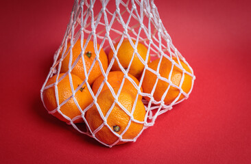 Eco-friendly mesh with tangerines on a red festive background.
