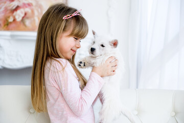child hugs a white terrier puppy