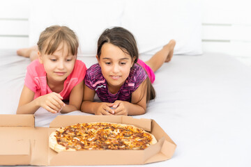 Two little girls eating pizza at home