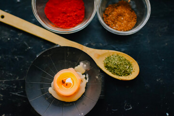 spices and herbs on spoons burning candle on black background