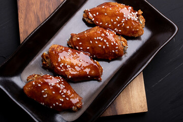 Fried chicken wings with spicy and sweet Korean sauce topped with white sesame seeds