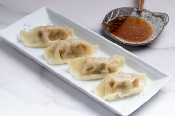 Pork gyoza in a white plate with soy sauce