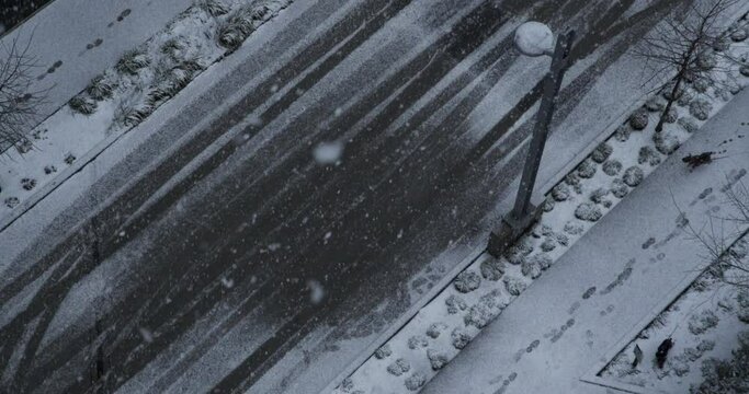 Top-down view of a snowy road and street lights during a snowfall in Vancouver, Canada