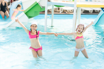 Two little girls fun jumping into the swimming pool