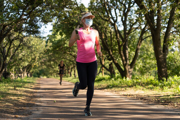 Stay in fit during quarantine. A sportive young woman is jogging outdoor, she have protective mask on face. Running alone of the Corona Virus or Covid-19.