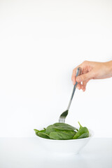 One hand with fork pricking spinach