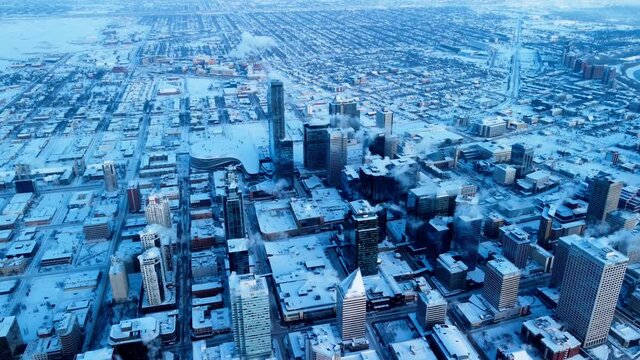 Edmonton city downtown winter aerial snow cover high rise building reflective mirrored glass financial residential commercial stadium towers reverse flight backwards at a mass altitude overlooking all