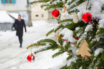 Beautiful Christmas tree detail and blurred people walking through the snow in winter day, in the...
