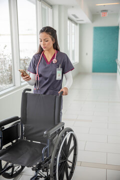 Female nurse pushing wheelchair in clinic corridor
