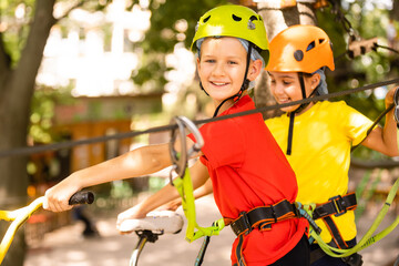 Adventure climbing high wire park - little boy on course in mountain helmet and safety equipment