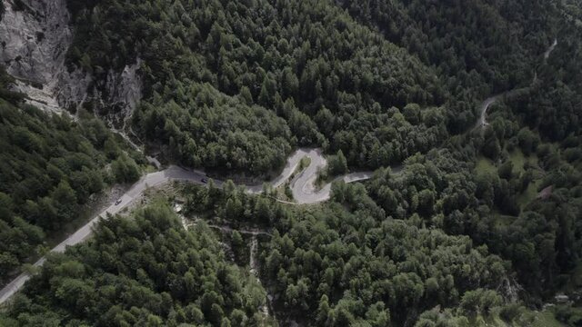 Drone video with side view "slider" and bird's eye view over the Vrsc pass in Slovenia with vehicles going up curvy road.
