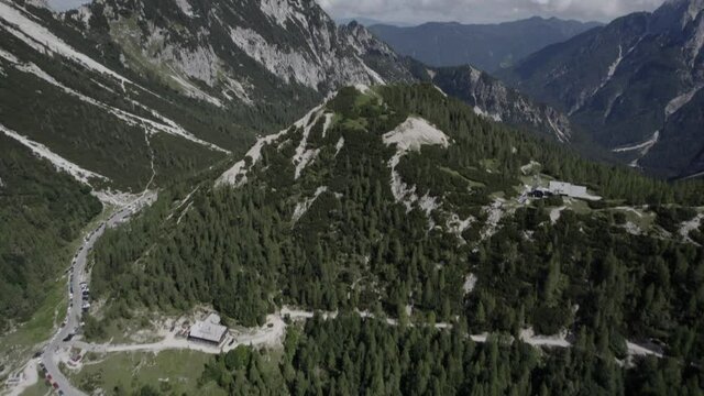 Drone video with descriptive frontal shot over the Vrsc pass in Slovenia with mountains on the horizon.