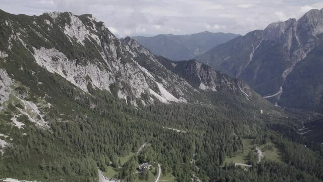 Drone video with revealing shot over the Vrsc pass in Slovenia with mountains on the horizon.
