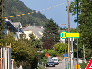 Selective blur on a typical austrian and german bus stop sign, called haltestelle, or bushaltestelle, in a suburban environment. it indicates the presence of a public transportation stop station...