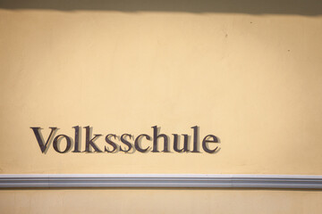 Sign indicating Volksschule, meaning in german People's school, on a building in Austria. Volksschule in Germany, Austria and Switzerland englobes primary and secondary school levels for students