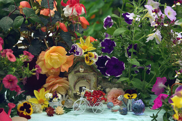 Lovely summer still life with tiny bicycle, doll house, flowers and berries in the garden.
