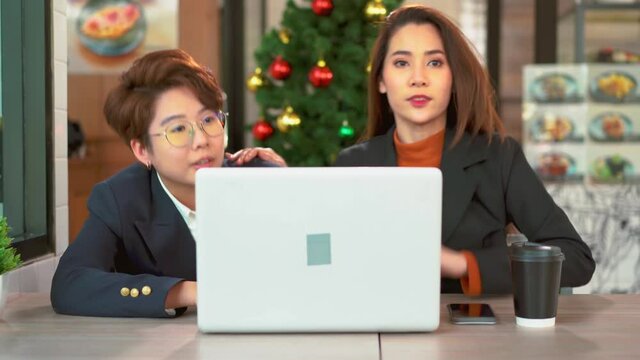 Romantic two same-sex lovers sit in a cafe kissing and hiding behind the tablet computer shocked after when someone sees So hurry up and act normal