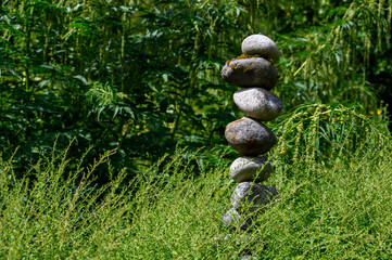 Fototapeta na wymiar Meditation space in peaceful garden with river rock stack, serene green foliage 