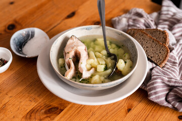 Flatley. On the table is a plate of fish soup, two slices of bread, rosettes with salt and pepper. Dinner.