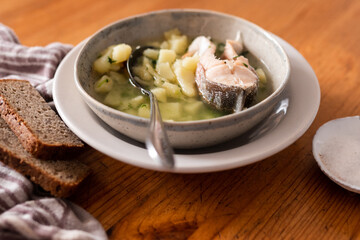 Flatley. On the table is a plate of fish soup, two slices of bread, rosettes with salt and pepper. Dinner.