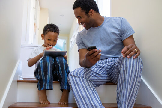 Father and son using digital tablet together while sitting on steps