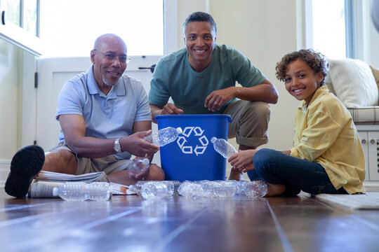 Multi-generation family recycling together on wooden floor