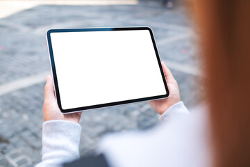 Mockup image of a woman holding digital tablet with blank white desktop screen in the outdoors
