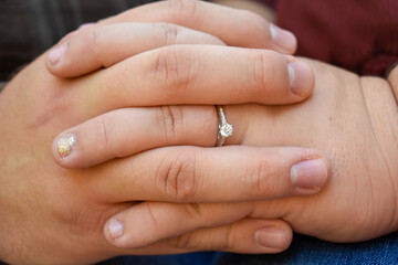 Closeup view of entwined fingers of an engaged couple. The entwined fingers show the love of the couple and how their lives will change. 