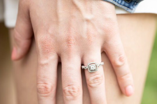 Manicured hand of newly engaged bride. Elegant silver diamond ring. Engagement photo shoot.  Calm romantic thoughts about the future.