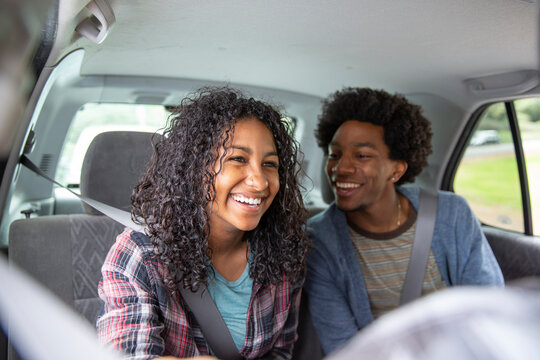 Happy young man with arms around female friends sitting in truck