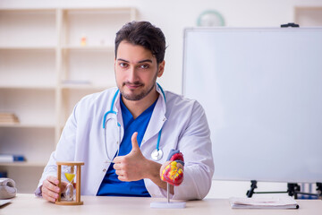 Young male doctor cardiologist in time management concept