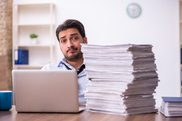 Young businessman employee unhappy with excessive work in the office