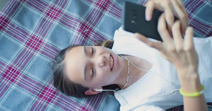 Top view of a teenager girl playing video game touching smartphone screen - she having fun at home.