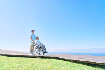 介護士と車椅子に乗る高齢者　屋外
