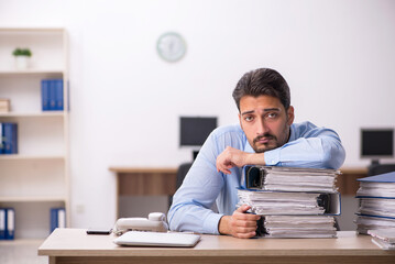Young male employee and too much work in the office