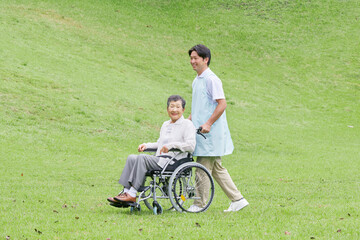 Fototapeta premium 介護士と車椅子に乗る高齢者 屋外