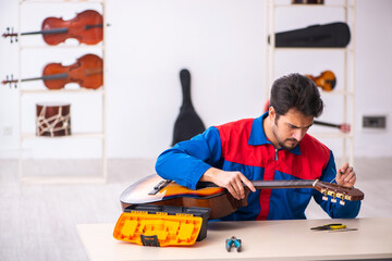 Young male repairman repairing musical instruments at workplace