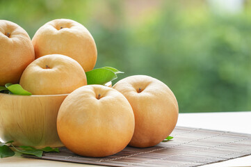 Snow pear fruit in wooden basket, Fresh Nashi pear or Korean pear fruit in the basket over green natural Blur background.