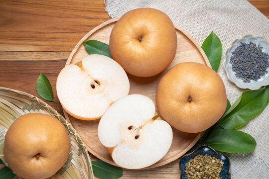 Premium Korean Sweet Pear with slice in wooden plate, Fresh Nashi pear or Korean pear fruit in wooden plate on wooden background.