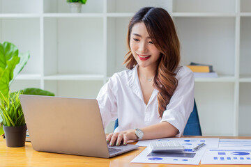 Fototapeta na wymiar Businesswoman typing company sales data on computer, woman sitting in a chair looking at financial documents on desk, accountant checking company numbers, modern businessman concept.