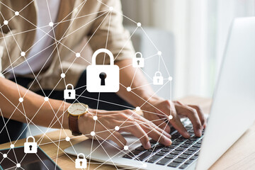 Young businessman wearing brown shirt hand holding and using laptop on desk, select the icon security on the virtual display. Business, technology, internet and networking concept.