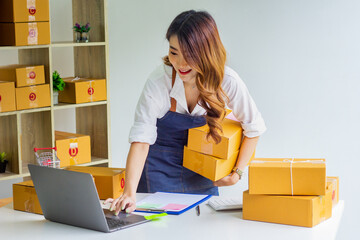 Small business owner looking at company's past online sales, cropped image of woman holding her own box for delivery at online sales office, merchandising concept and modern businessman.