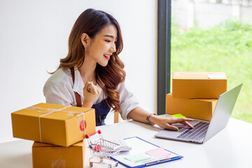 An online business owner checks the name and address of a customer ordering a company product, Cropped photo of a woman checking and writing the name on a parcel for delivery at an online sale office.