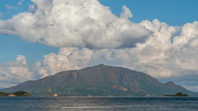 The famous mountain peak, Mont Dore in New Caledonia as seen from across the bay with huge cumulus clouds forming and dissipating above the island - time lapse