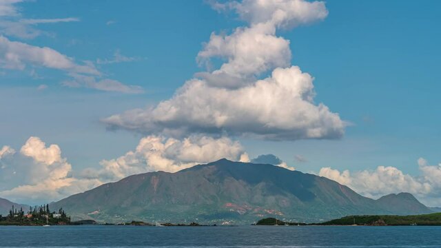 A view of the mountain peak, Mont Dore on the Grande Terre Island of New Caledonia with sailboats in the harbor and a cloudscape overhead - wide angle time lapse